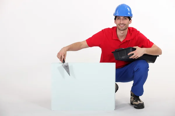 Portrait of attractive bricklayer hunkering down with trowel and copyspace — Stock Photo, Image