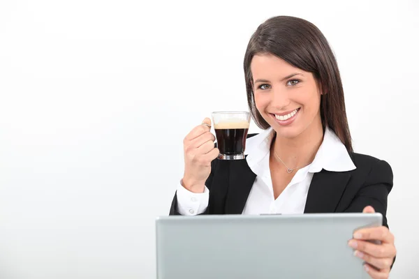 Женщина пьет кофе за своим ноутбуком — стоковое фото