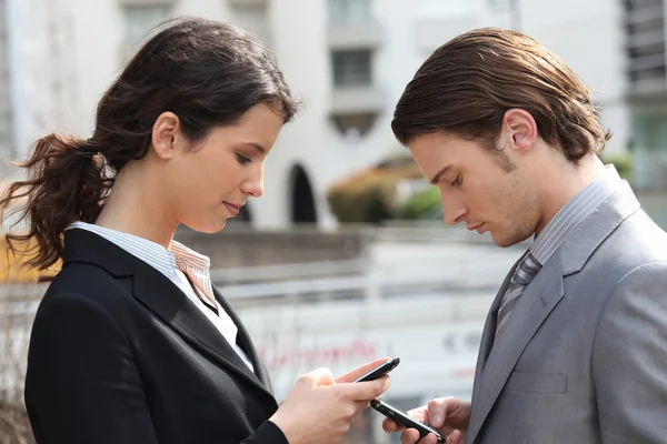 Casal de negócios mensagens de texto em celulares — Fotografia de Stock