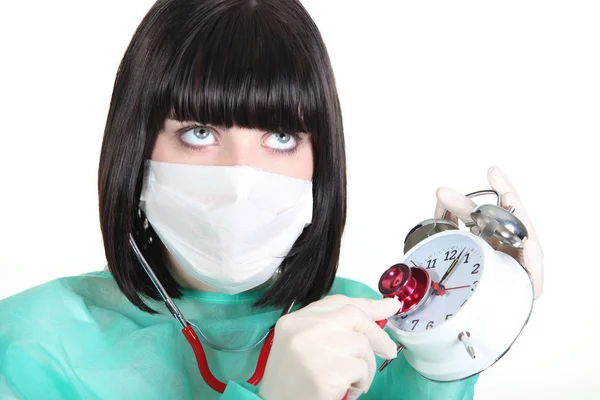 Vrouwelijke arts met behulp van stethoscoop op alarm clock — Stockfoto
