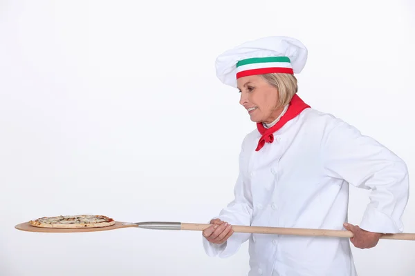 Итальянский повар кладет пиццу в духовку Лицензионные Стоковые Изображения
