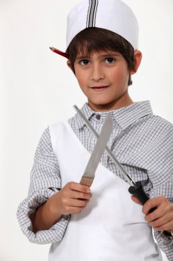 Young boy dressed as a butcher sharpening a knife clipart