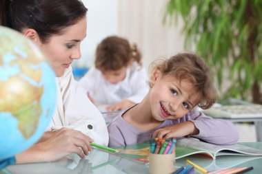 Teacher helping a pupil with her school work clipart