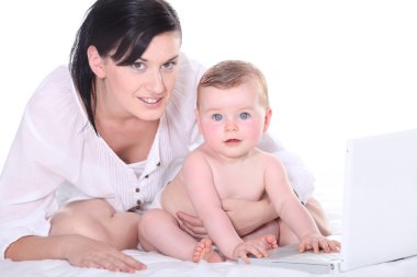 Mother with her baby and a laptop clipart