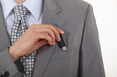 Businessman putting a flash drive in his pocket clipart