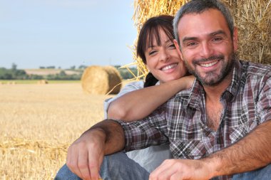 Farming couple sat by hay clipart