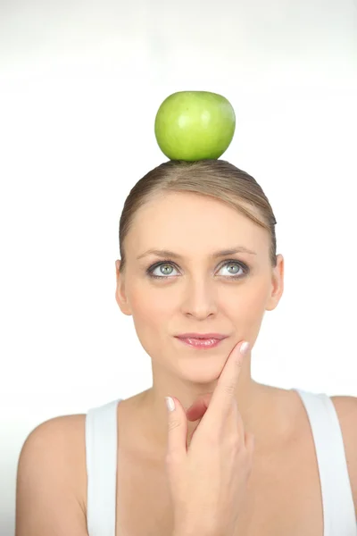 Молода жінка балансує зелене яблуко на голові — стокове фото