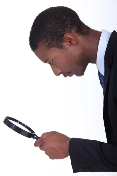 Black man looking through a magnifying glass — Stock Photo, Image