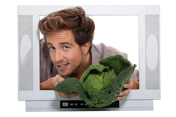 Man holding cabbage escaping from television — Stock Photo, Image