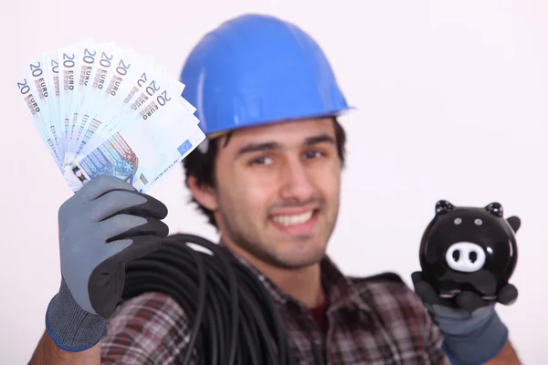 Construction worker with bills and piggy bank in hands — Stock Photo, Image