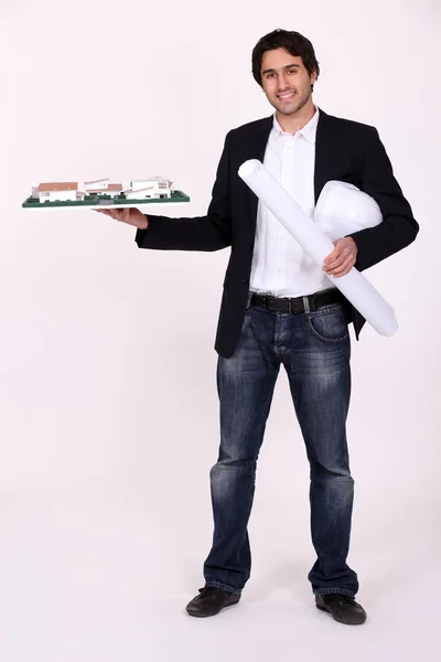 Architect holding a rolled-up blueprint and a building model — Stock Photo, Image