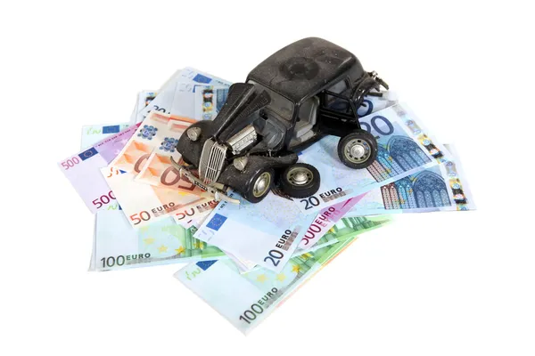 Broken retro car model laying over banknotes — Stock Photo, Image