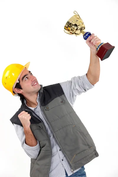 En byggnadsarbetare som innehar en trofé. — Stockfoto