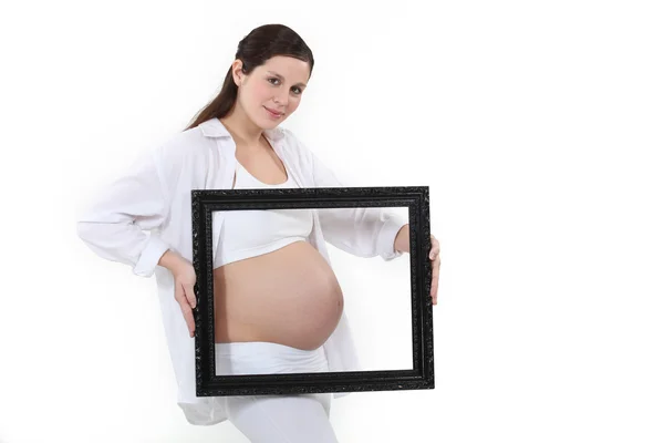 Pregnant woman carrying black frame — Stock Photo, Image