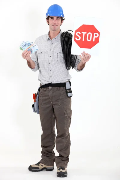 Eletricista segurando dinheiro e sinal de parada — Fotografia de Stock