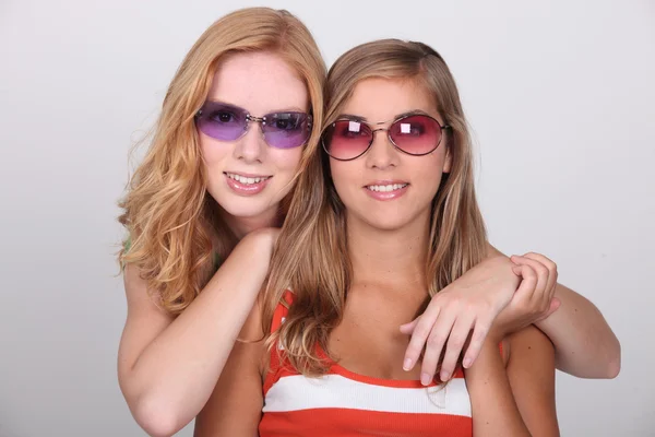 Studio shot of two pretty teenagers wearing colored sunglasses — Stock Photo, Image