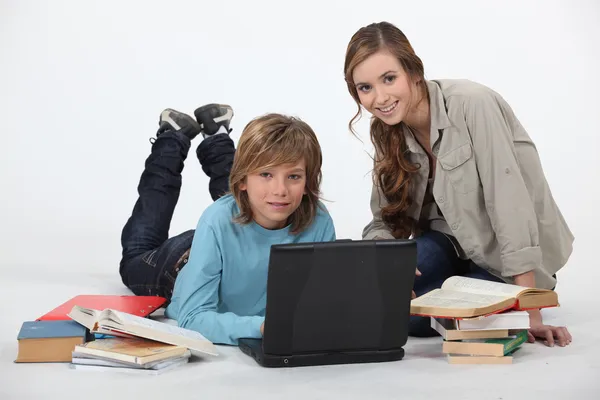 Tinédzser csinálja a házi feladatát laptoppal és nővérrel — Stock Fotó