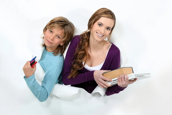 Female student holding books and younger brother — Stock Photo, Image