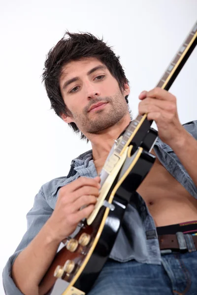 Молодий чоловік грає на електричній гітарі, його сорочка відкрита, фото зроблено — стокове фото