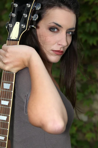 Mujer de pelo oscuro sosteniendo una guitarra parecía misterioso —  Fotos de Stock