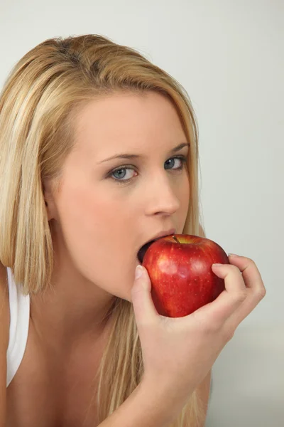 Mulher loira comendo maçã vermelha — Fotografia de Stock