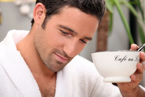 Человек в халате с чашкой кофе и ручкой — стоковое фото