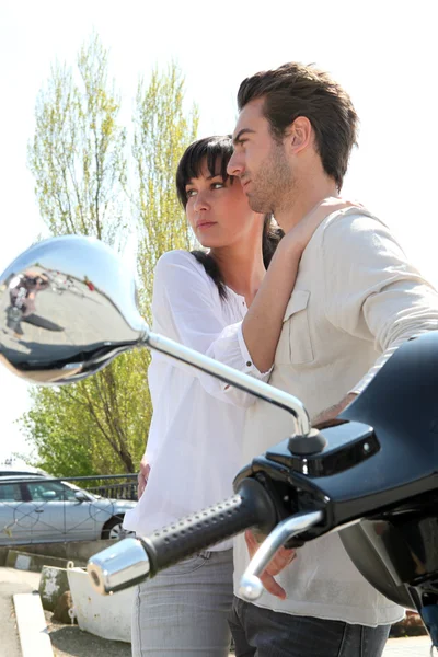 Couple standing next to a parked scooter — Stock Photo, Image