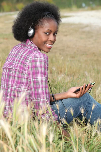 Donna che ascolta musica in un campo — Foto Stock