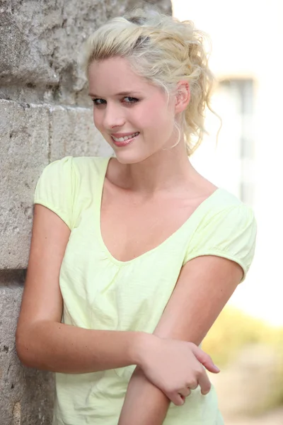 En fin blond poserar med en vägg. — Stockfoto