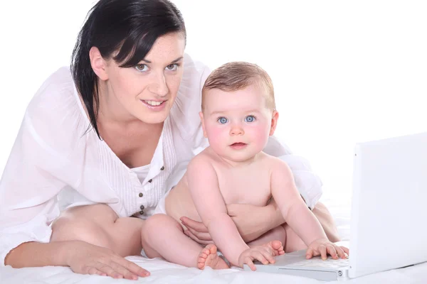 Moeder met haar baby en een laptop — Stockfoto