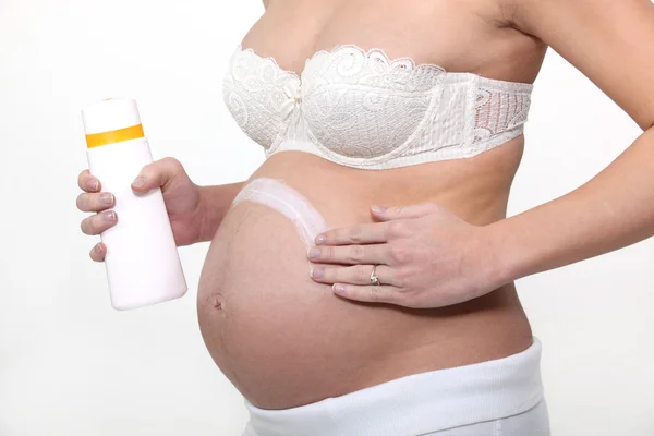 Pregnant woman applying cream on her belly — Stock Photo, Image