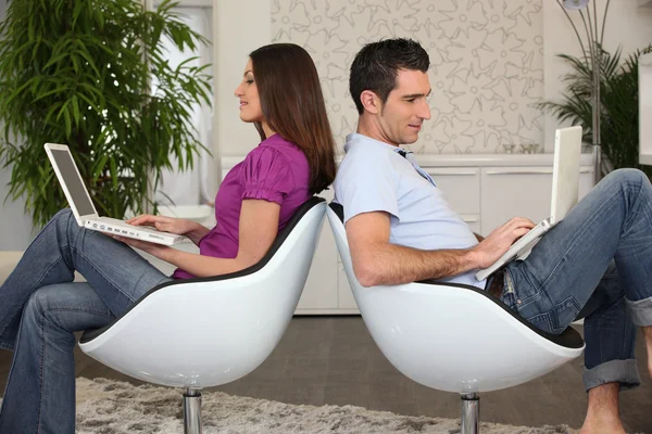 Mann und Frau sitzen Rücken an Rücken mit Computern — Stockfoto