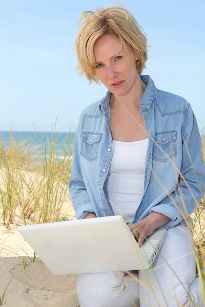 Vrouw op duinen met laptopcomputer — Stockfoto