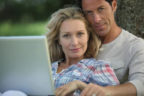 Paret satt i parken med laptop — Stockfoto