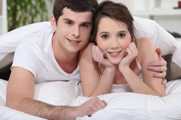 Jovem casal abraçando na cama — Fotografia de Stock