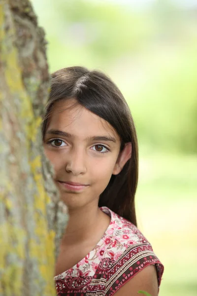 A little Latina hiding behind a tree. — Stock Photo, Image