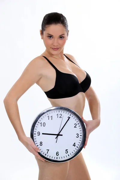 Woman in bra holding clock Stock Picture