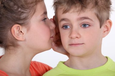 Little girl whispering secret to little boy's ear clipart