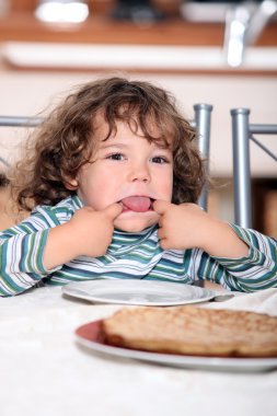 Toddler pulling a face at the table clipart