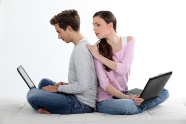 Young couple of cybernauts sitting cross-legged back to back clipart