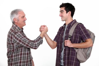 Mature man and young man handshaking clipart