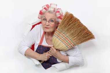 Granny with her hair in rollers holding a broom clipart