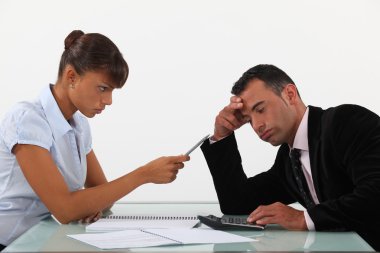 Stern woman with a man using a calculator clipart