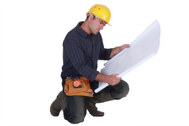 Frowning tradesman examining a blueprint clipart