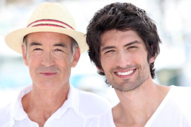 65 years old man wearing a straw hat and a 25 years old man posing in a sum clipart