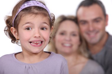 A cute little girl with her parents in the background. clipart