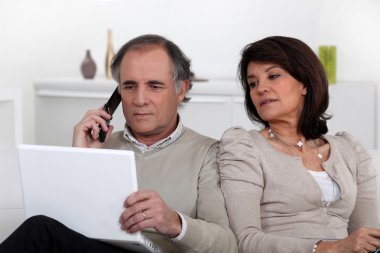 Nosy wife looking at her husband's laptop screen clipart