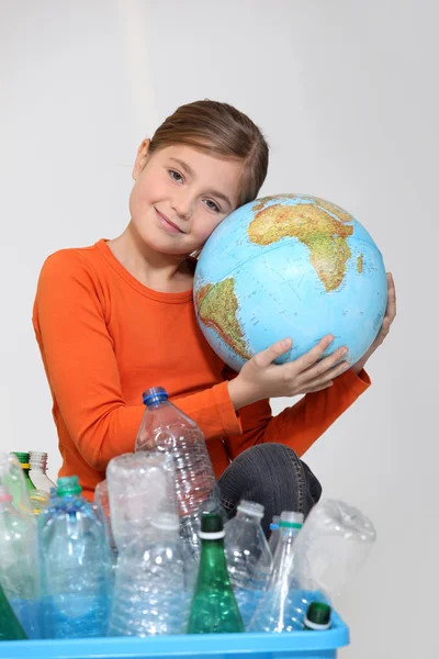 Jovencita abrazando un globo detrás de una caja de reciclaje de plástico — Foto de Stock