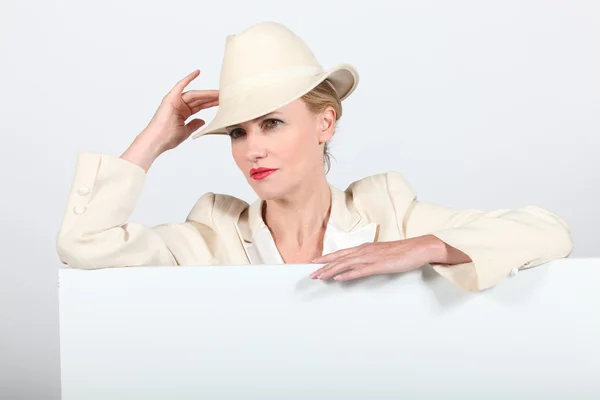 Kadın bir krem elbise ve fötr şapka ile boş tahta mesajınız için hazır — Stok fotoğraf