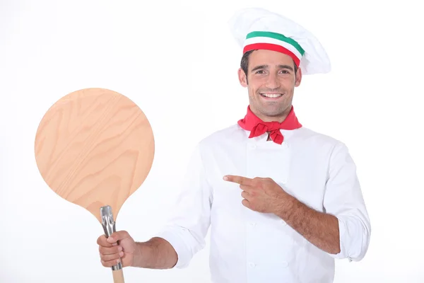 Итальянский шеф-повар указывает на деревянную кожуру для пиццы — стоковое фото